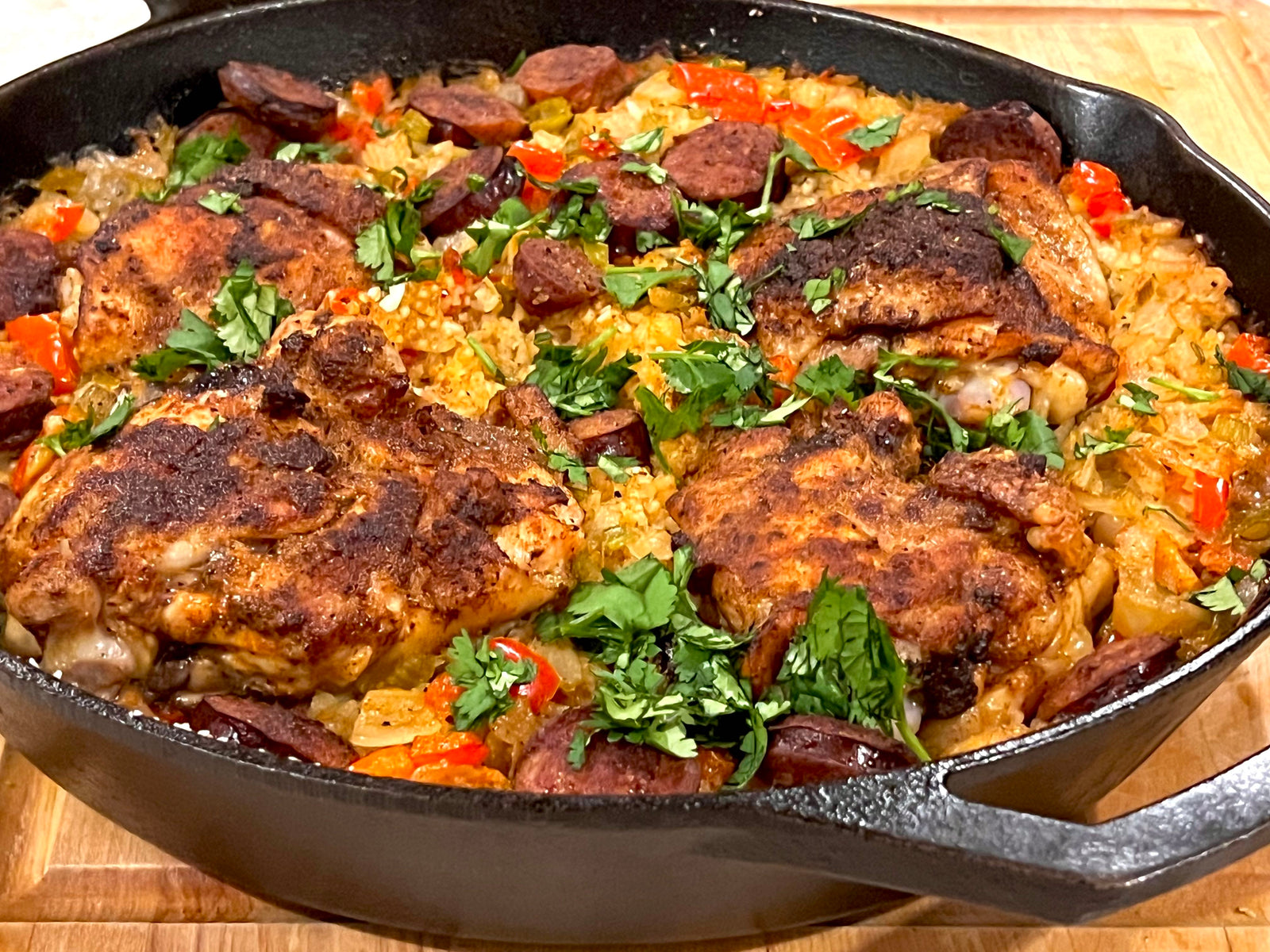 Creole Kiss Chicken Thighs in cast iron skillet with rice grits