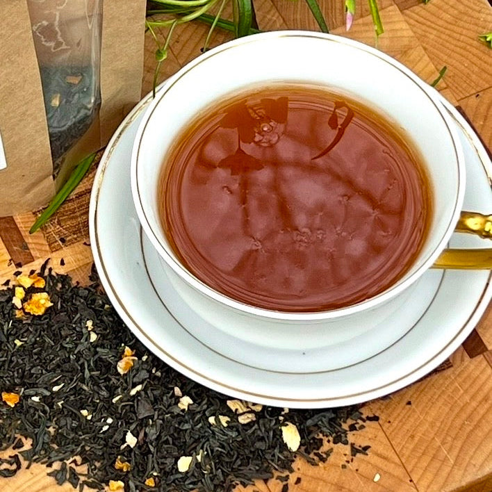 Tea cup with tea leaves and flowers on a wooden surface