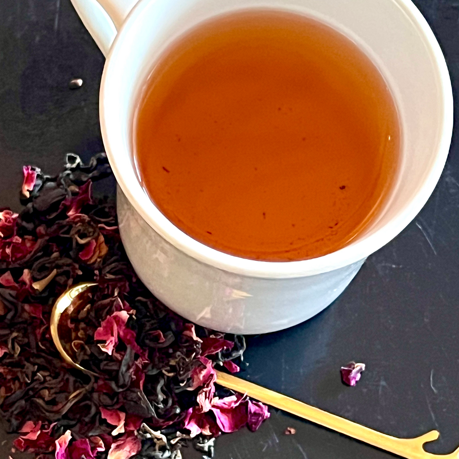 Rose & Cardamom Tea Blend image in white cup with loose leaf tea beside on gold spoon
