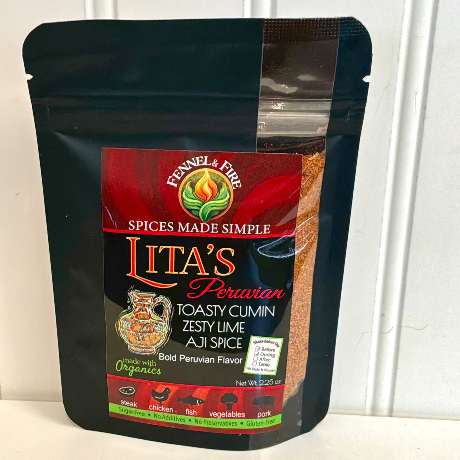 A black resealable stand-up pouch of Lita's Peruvian Toasty Cumin Zesty Lime Aji Spice, displayed on a white surface against a white paneled wall.