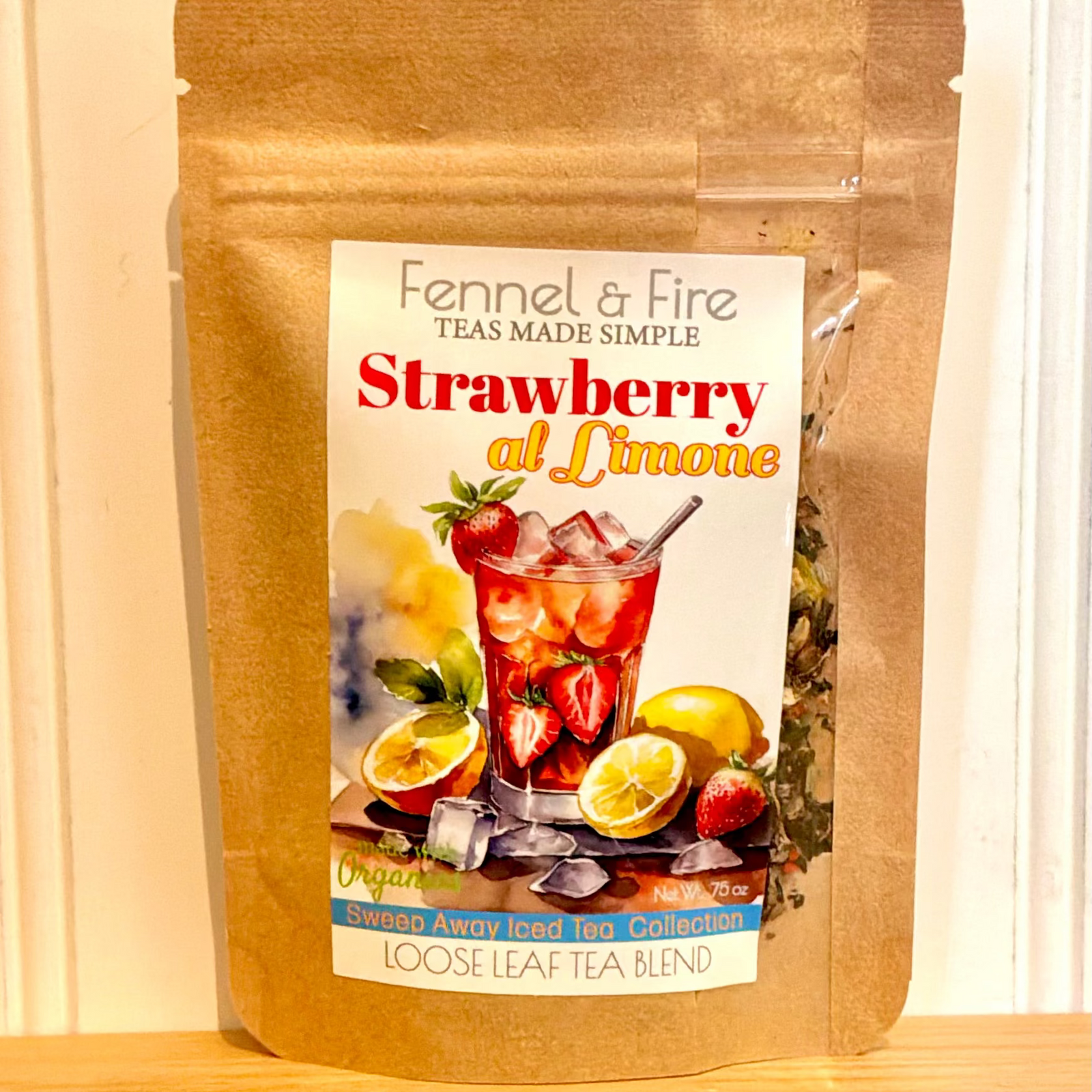 Fennel & Fire Strawberry al Limone tea package on a wooden surface with a white background