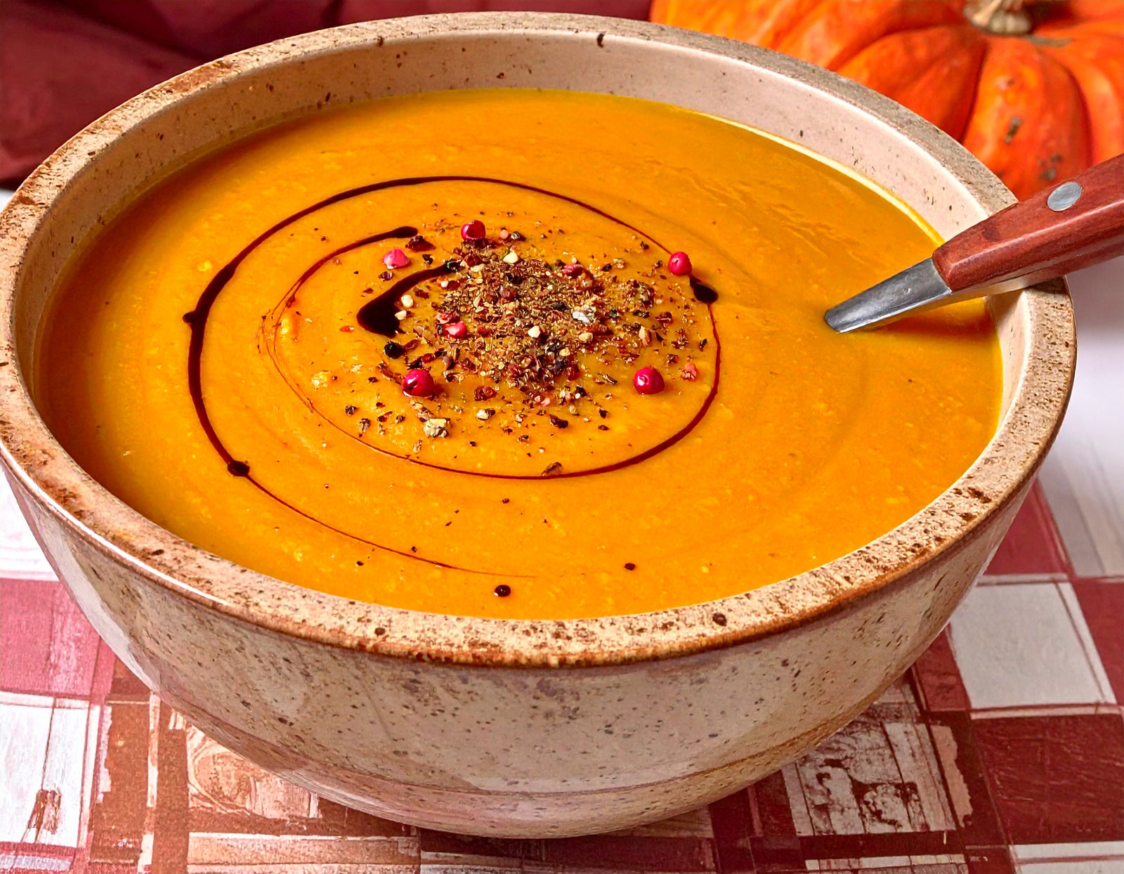 Image of bowl of pumpkin soup with drizzle of balsamic vinegar and pink and pink