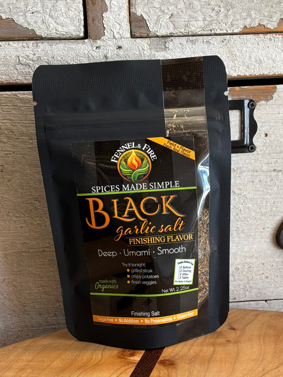 Black garlic salt packaging on a wooden surface with a rustic background