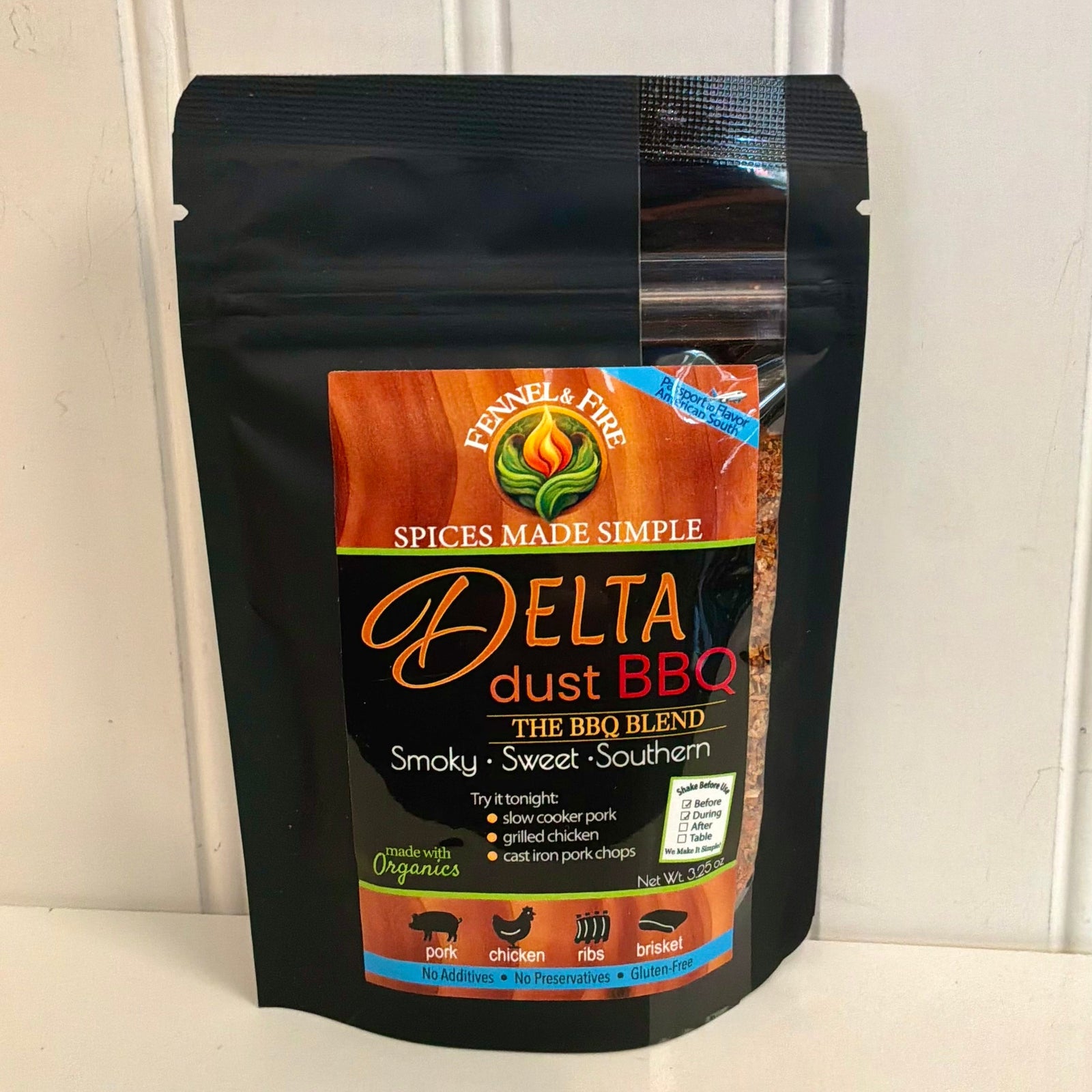 A black resealable stand-up pouch of Fennel Fire Delta Dust BBQ spice blend, shown against a white paneled wall and countertop.
