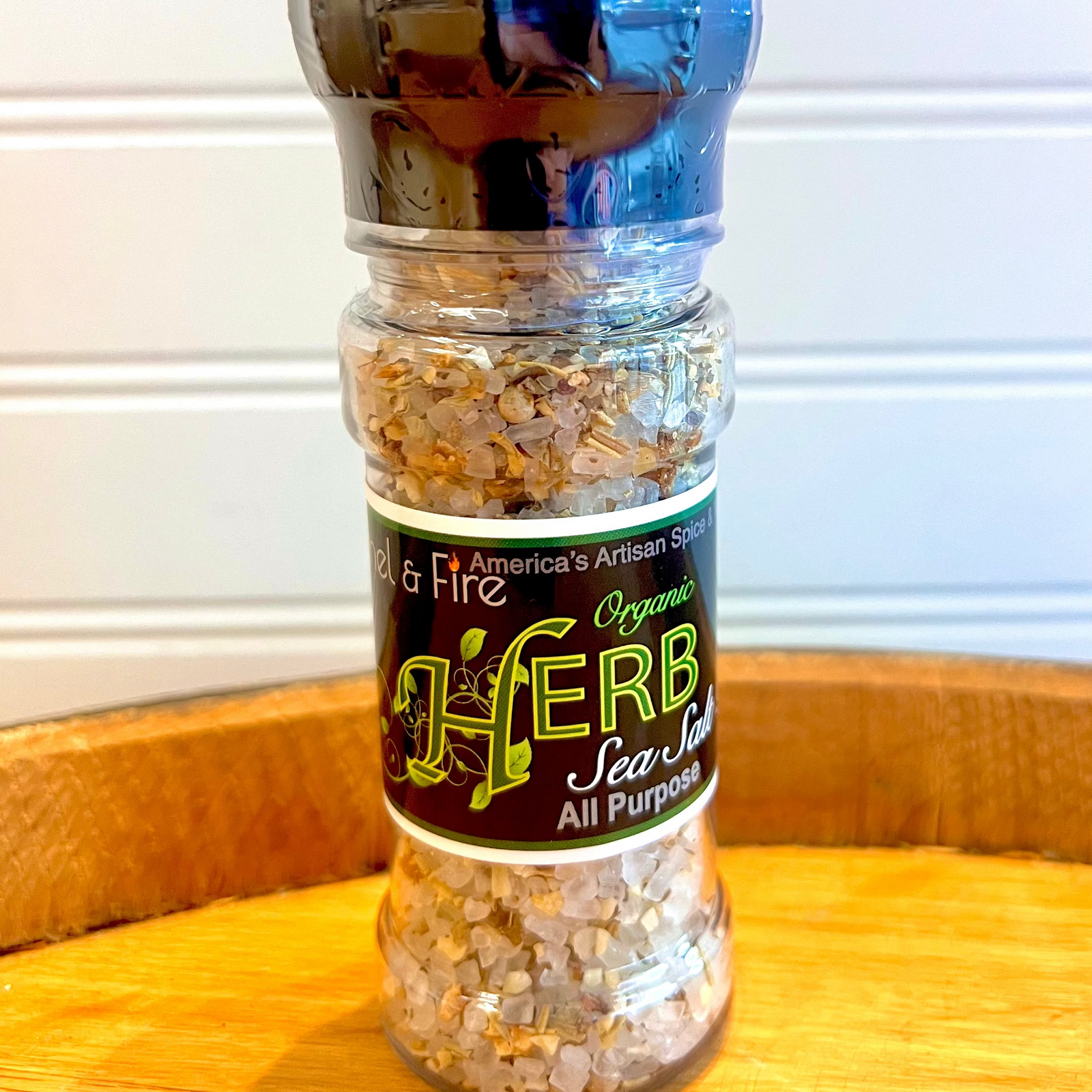 Herb sea salt grinder on a wooden surface with a white background