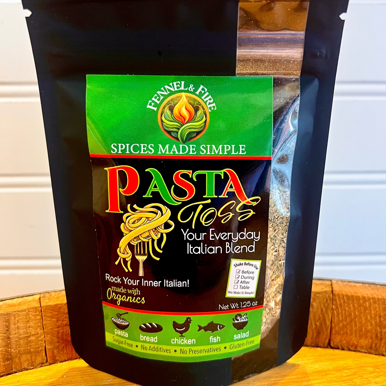 Bag of Pasta toss seasoning on a wooden barrel with a white background.