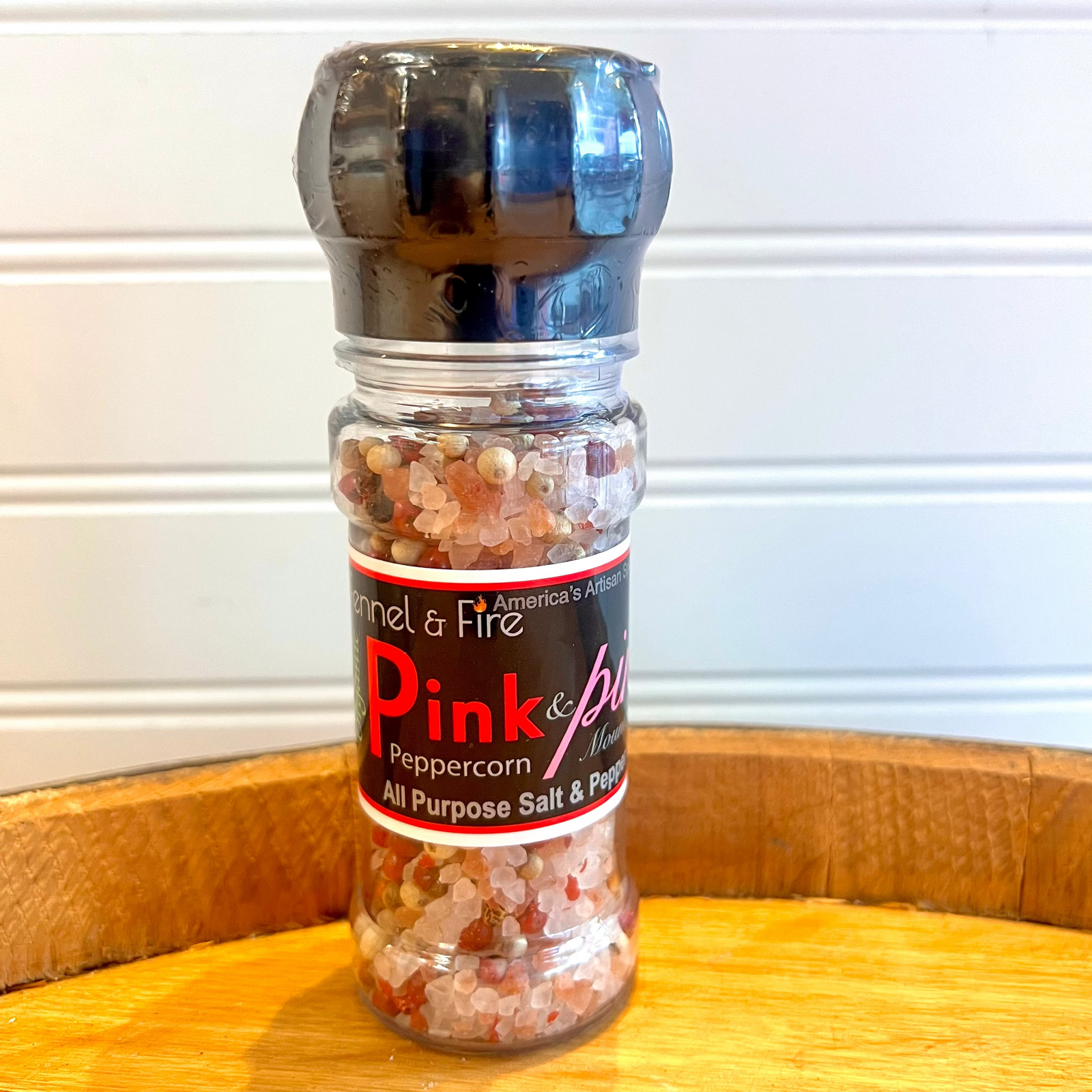 Bottle of Pink & White  salt and pepper on a wooden surface with a white background