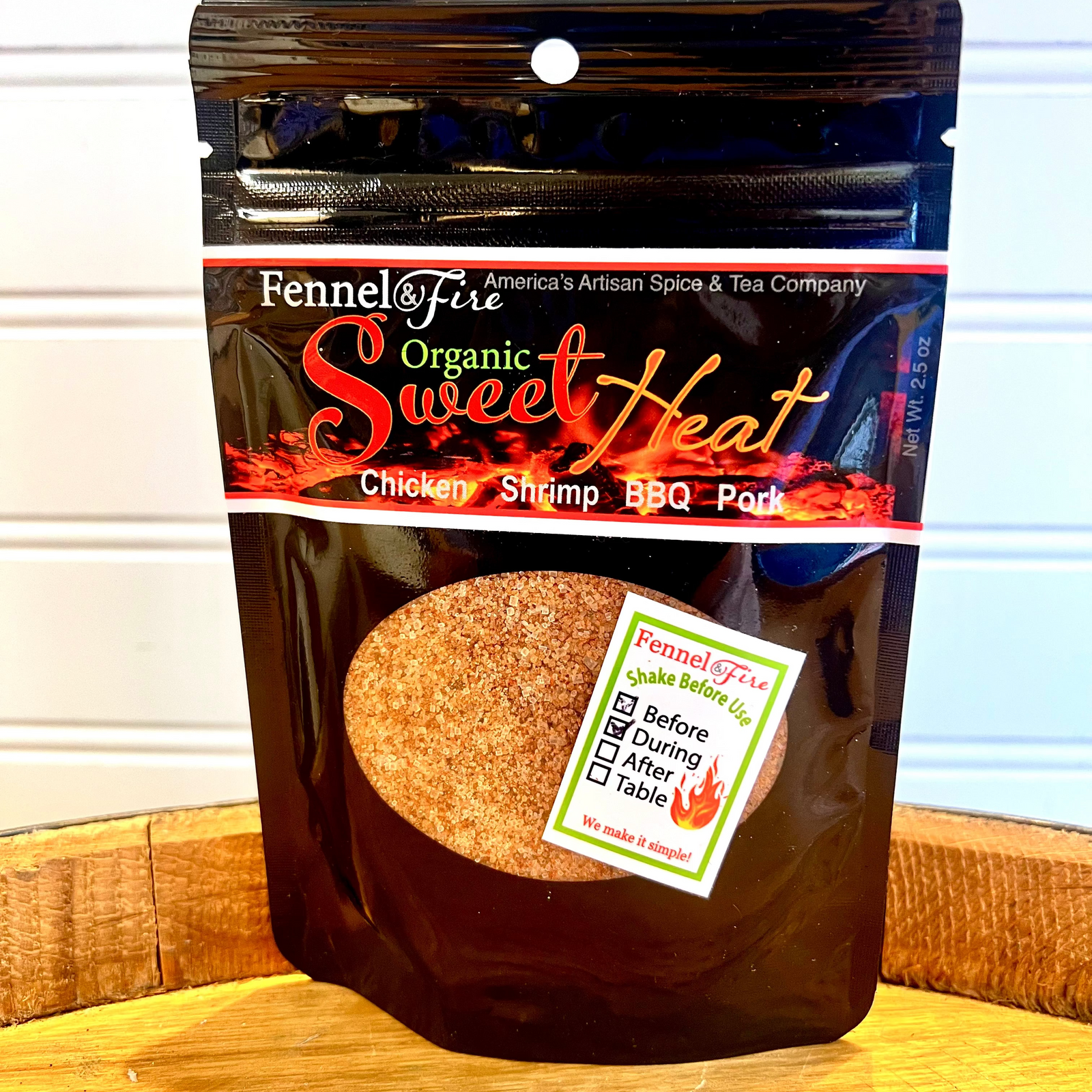 Fennel & Fire Organic Sweet Heat spice package on a wooden surface with a white background