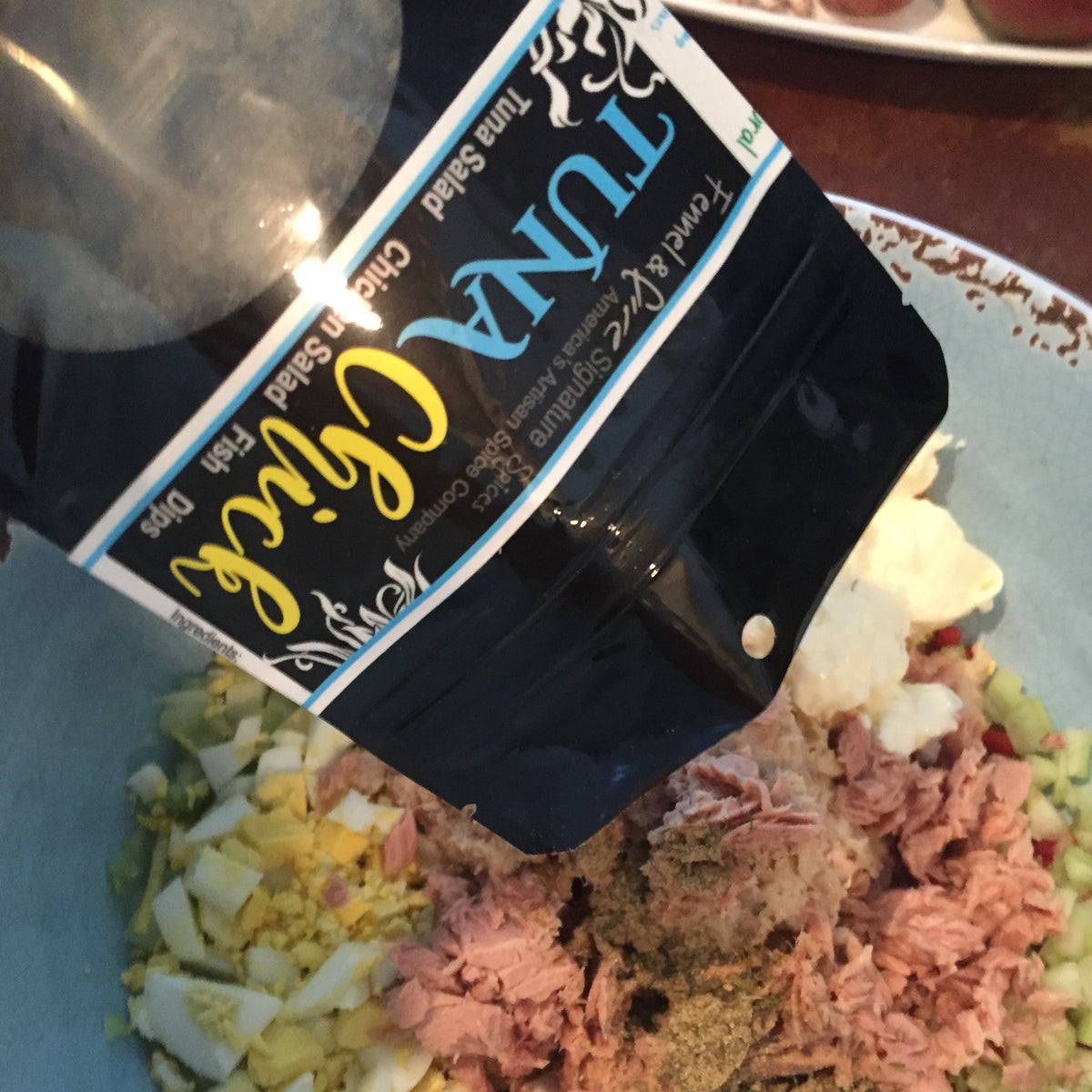 bag of tuna chick spice blend pouring into tuna salad. 